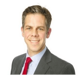 A professional man in a suit and red tie smiling against a white background.