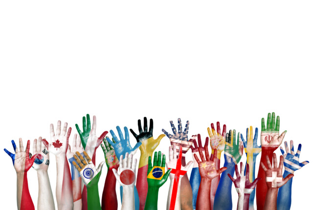 A vibrant display of unity in diversity: colorful hands painted with various national flags reaching upwards against a white background.