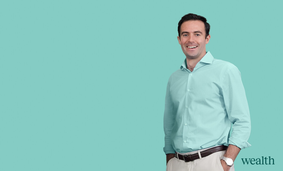 Confident businessman in a light blue shirt smiling against a teal background, with the word "wealth" suggesting financial themes.