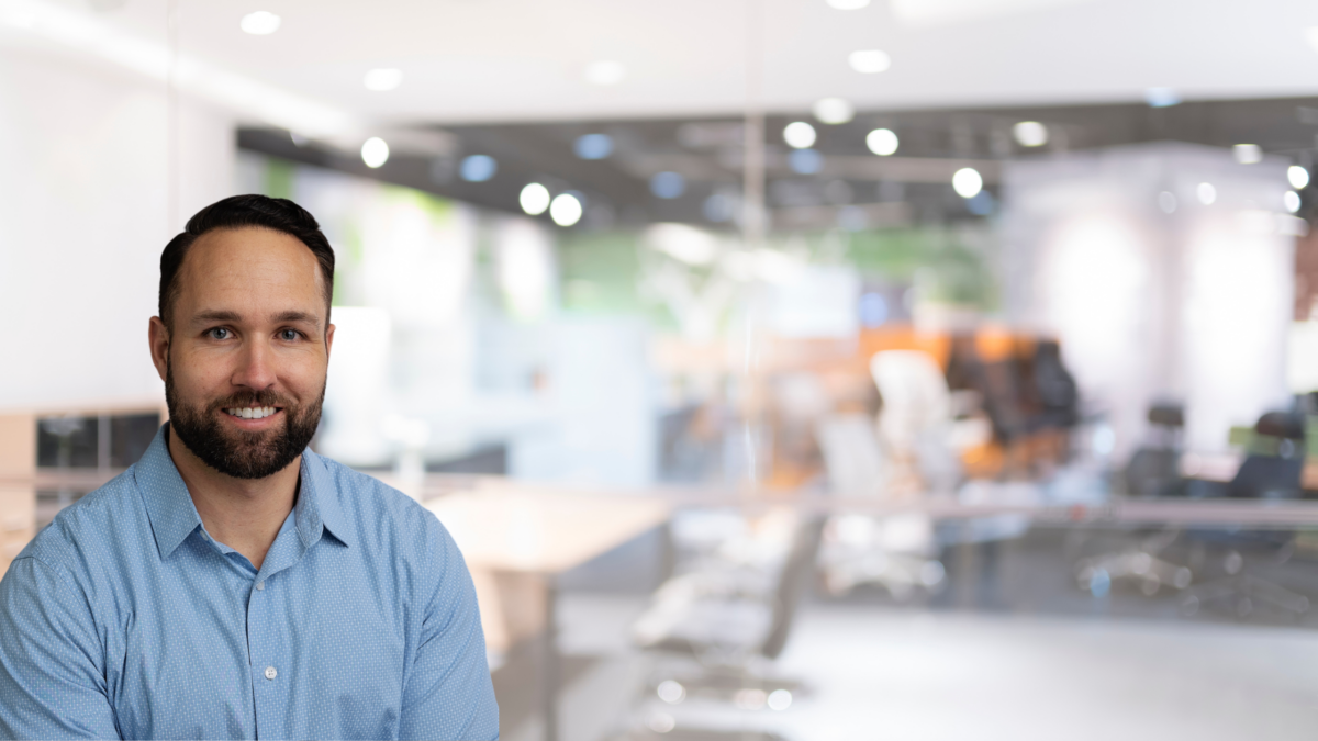 A confident professional man smiling in a modern office environment.