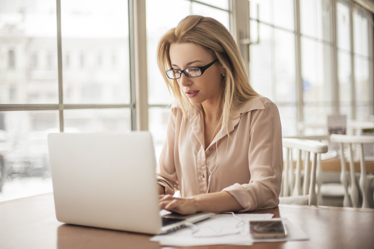A focused woman working on her laptop in a bright and airy cafe setting.