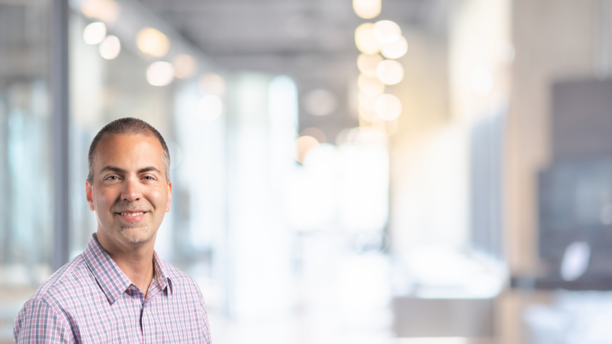 Confident professional posing with a smile in a bright modern office environment.