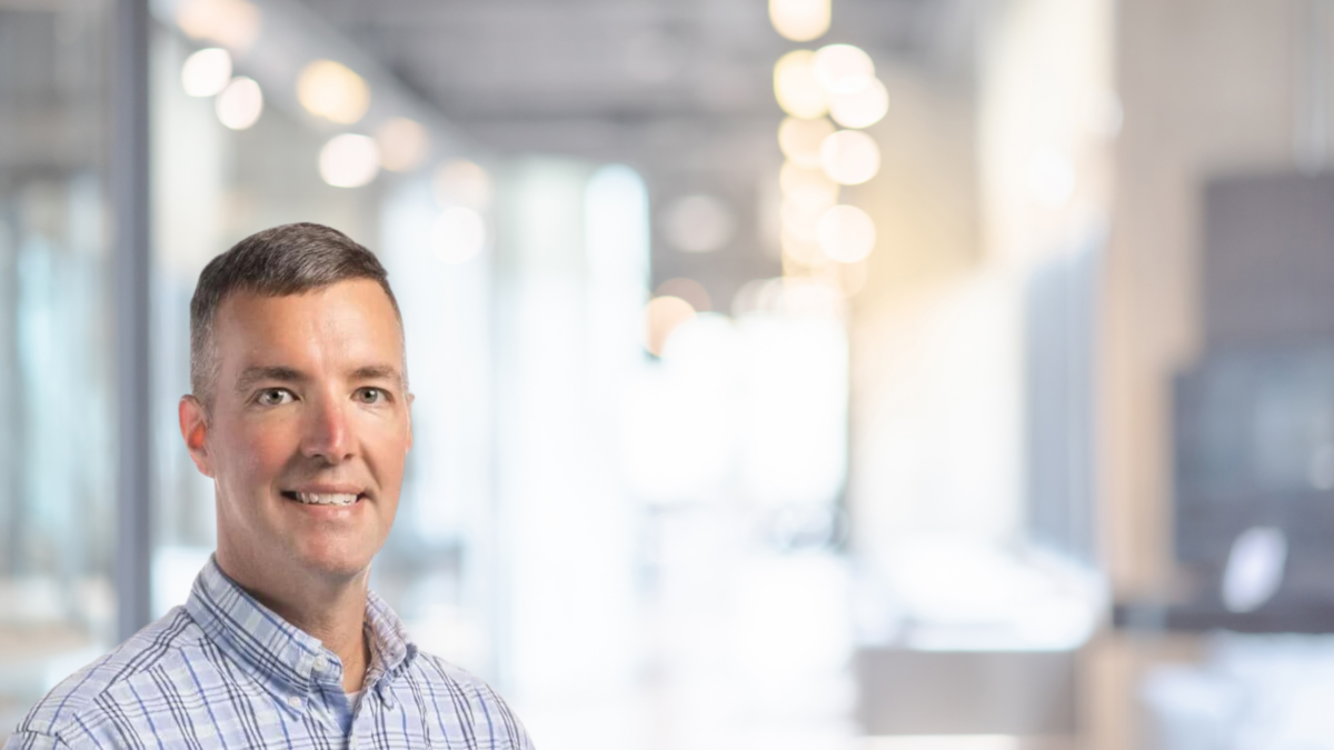 Confident professional smiling in a modern office setting with ambient lighting.