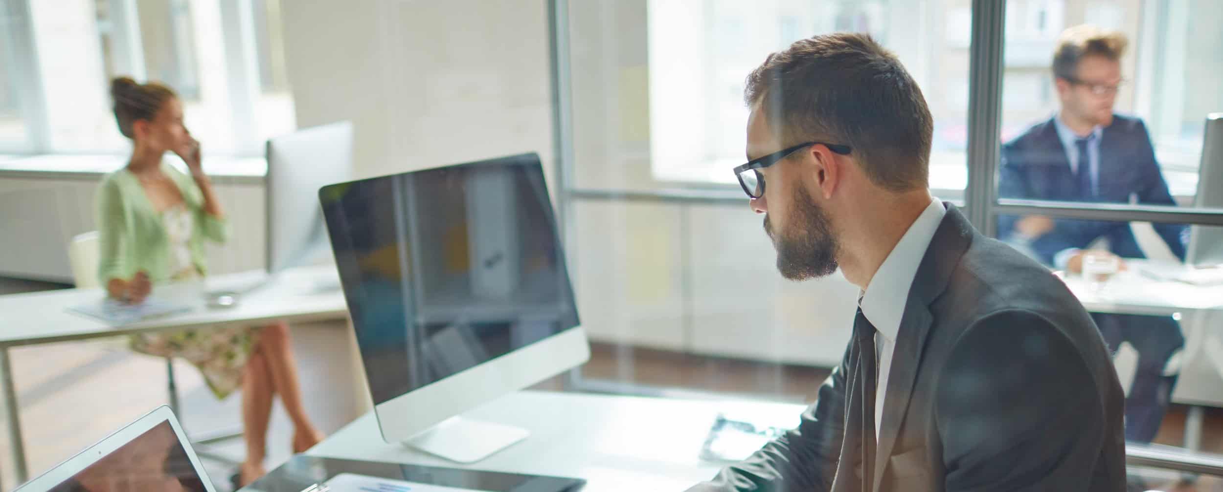 Professionals at work in a modern, bright office space, focusing on their tasks with concentration and dedication.