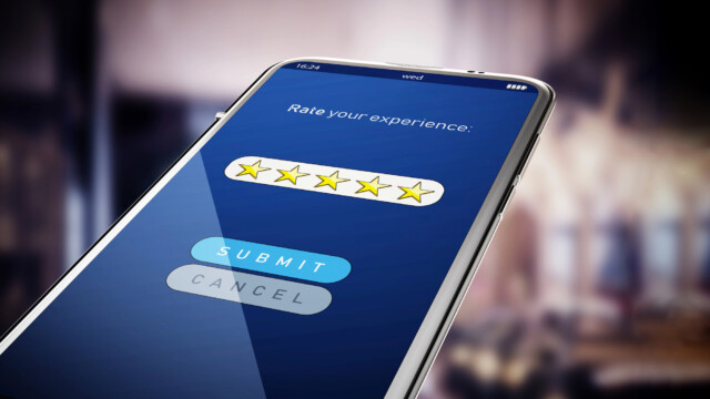 A smartphone screen displays a "Rate your experience" survey with five yellow stars selected, and "Submit" and "Cancel" buttons below on a blue background. The phone is held up in a blurred indoor setting.